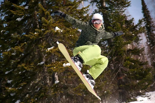 Snowboarder springen door lucht bos op achtergrond — Stockfoto