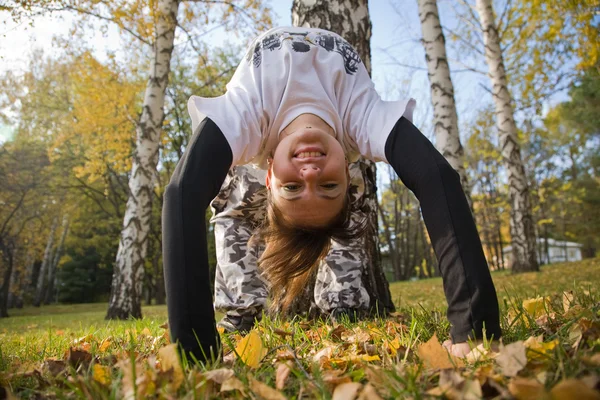 stock image A young woman makes a handstand on grass in front of blue sky