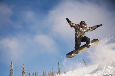 Snowboarder jumping through air with deep blue sky in background clipart