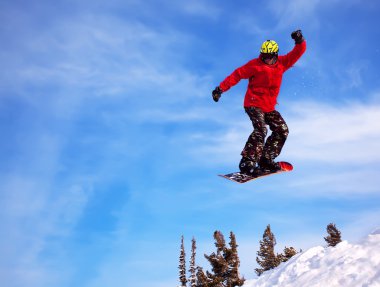 Snowboarder jumping through air with deep blue sky in background clipart