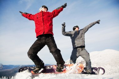 Happy snowboarding team in winter mountains clipart