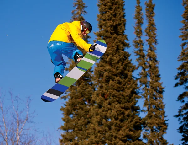 Snowboarder jumping through air with deep blue sky in background — Stock Photo, Image