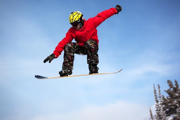 Snowboarder che salta attraverso l'aria con cielo blu profondo sullo sfondo — Foto Stock