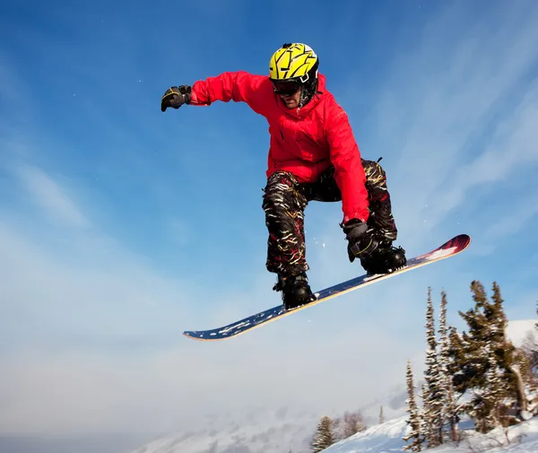Snowboarder jumping through air with deep blue sky in background — Stock Photo, Image