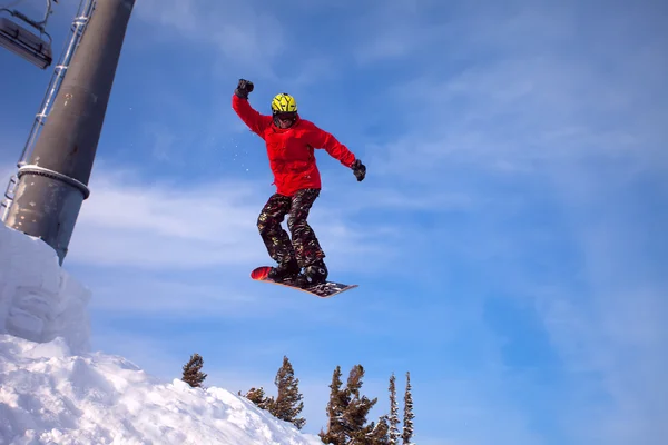 Сноубордист прыгает по воздуху с глубоким голубым небом на заднем плане — стоковое фото