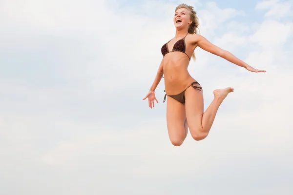 Женщина прыгает по пляжу — стоковое фото