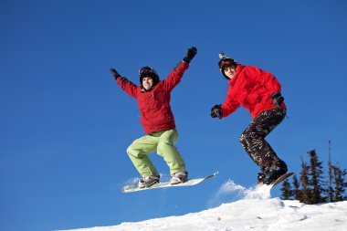 Snowboarder jumping through air with deep blue sky in background clipart