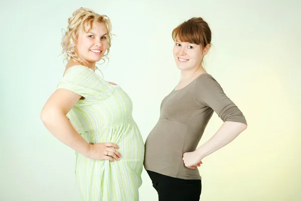 Duas engraçadas grávidas usando suas entranhas grandes isoladas — Fotografia de Stock