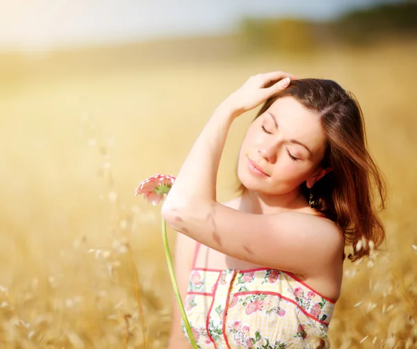 Чарівна жінка в полі з квіткою — стокове фото