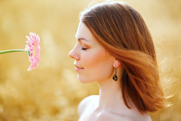 Menina encantadora com uma flor em um campo de verão — Fotografia de Stock