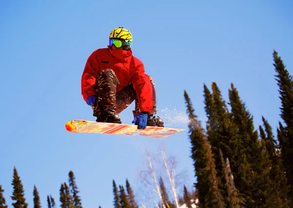 Snowboarder che salta attraverso l'aria con cielo blu sullo sfondo — Foto Stock