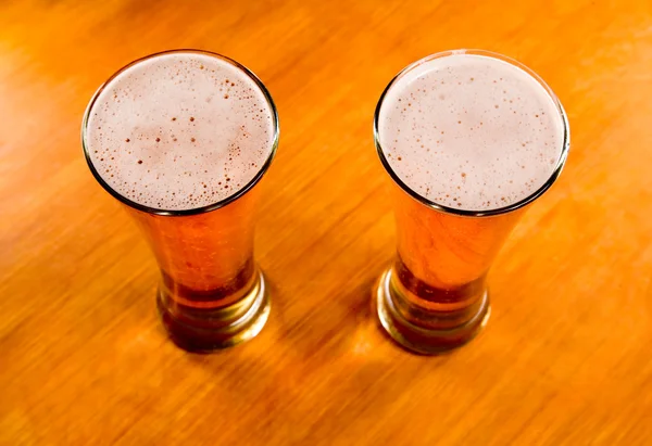 Ahşap masa üstünde iki bira bardağı — Stok fotoğraf