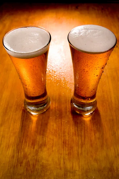 Два бокала пива на мокром деревянном фоне — стоковое фото