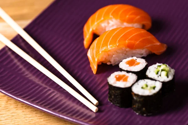 Deliciosos rolos de sushi com pauzinhos — Fotografia de Stock