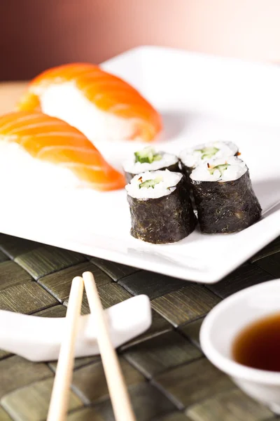 Роллы суши на белой тарелке с палочкой — стоковое фото