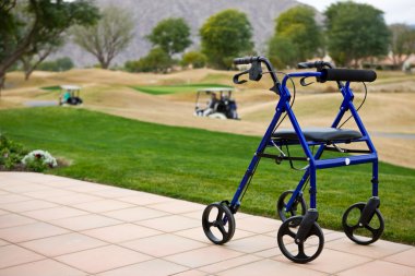 Walker Outdoors On A Patio With Golf Course In Background clipart