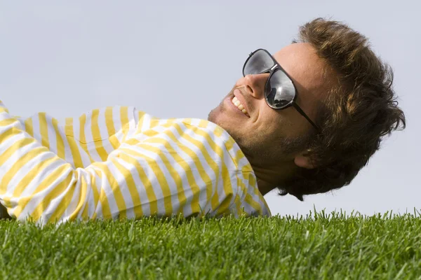 Junger Mann legt sich ins Gras — Stockfoto