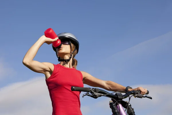 Женщина пьет воду на велосипеде — стоковое фото