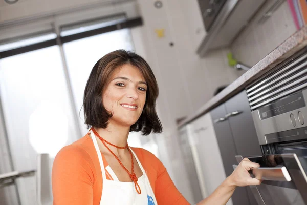 Mulher abrindo o forno de cozinha — Fotografia de Stock