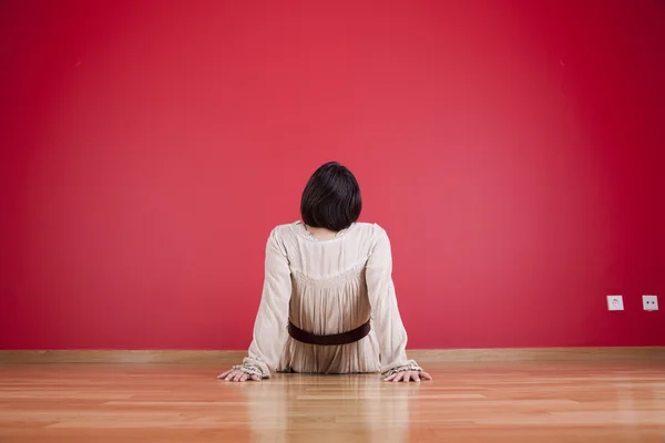Woman looking to a red wall — Stock Photo, Image