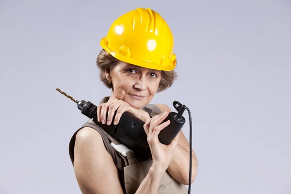 Senior woman with a drill tool — Stockfoto