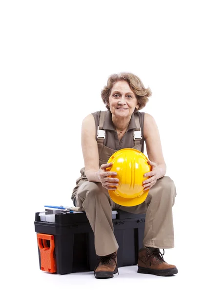 Senior woman sitting in a toolbox — Stock Photo, Image