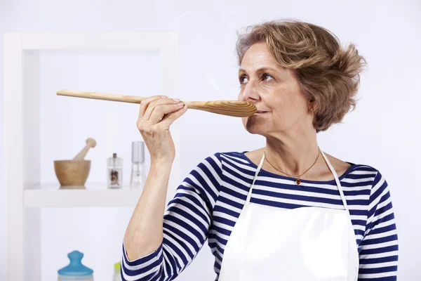 Äldre kvinna provsmakning mat — Stockfoto