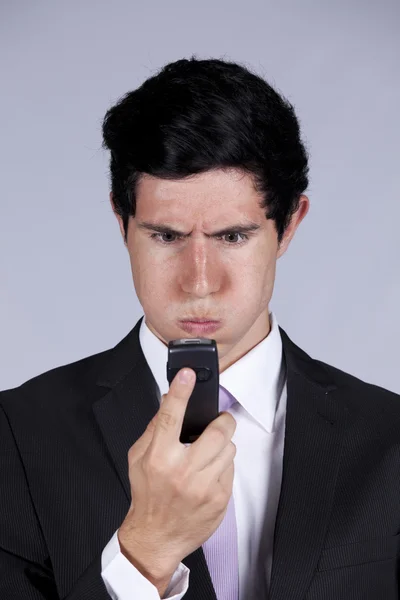 Злий бізнесмен дивиться на свій мобільний телефон — стокове фото