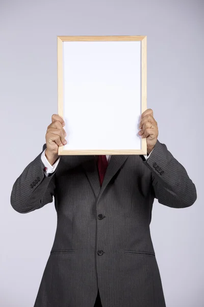 Empresário segurando um quadro branco — Fotografia de Stock