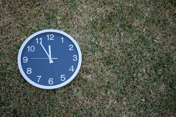Relógio de parede na grama — Fotografia de Stock