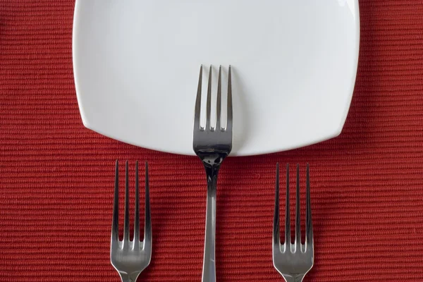 Три вилки и фарфоровая тарелка — стоковое фото