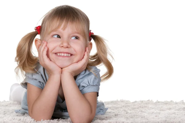 Cheerful little girl lying on the carpet — Stock Photo, Image