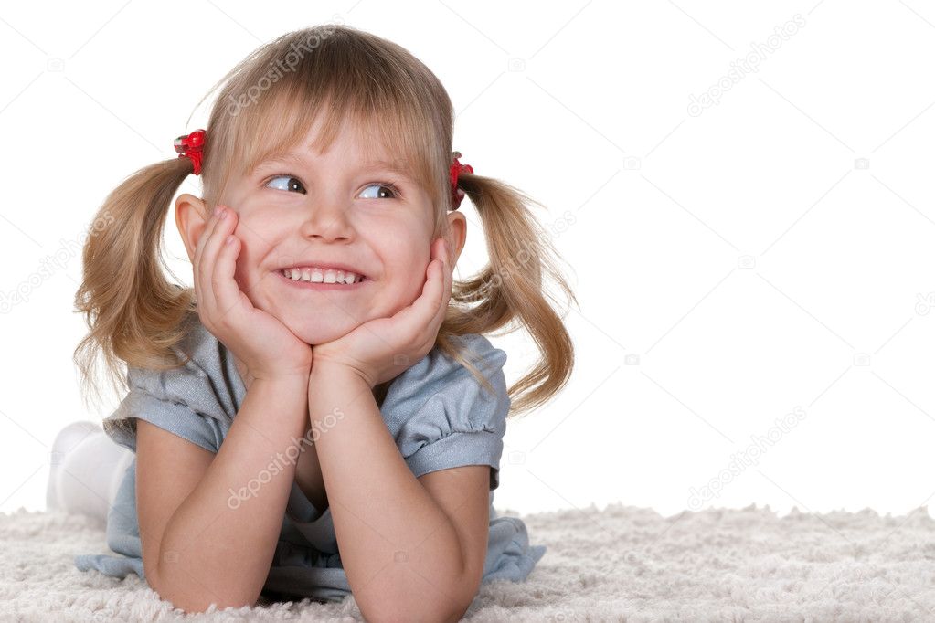 Cheerful little girl lying on the carpet