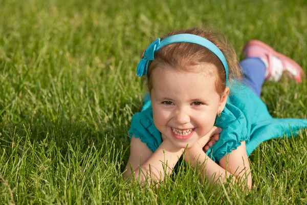 Wesoła, uśmiechnięta dziewczynka na zielonej trawie — Zdjęcie stockowe