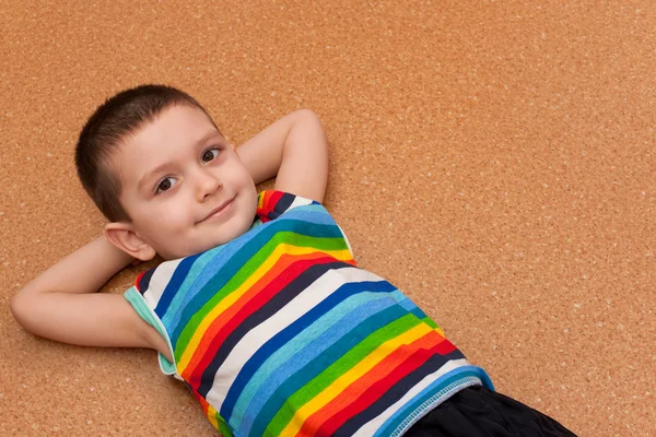 Fröhlicher kleiner Junge auf dem Boden liegend — Stockfoto