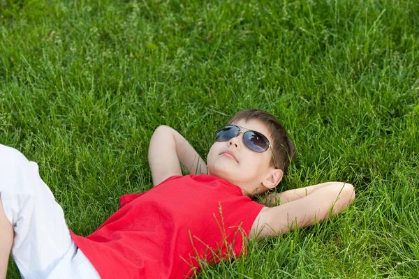 Мечтающий мальчик на траве — стоковое фото