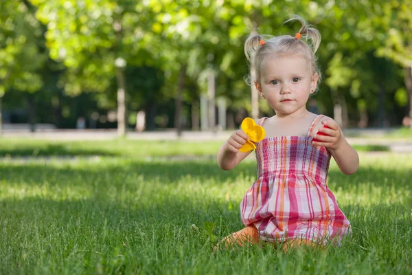 Little girl with toys in the park — Stock Photo, Image
