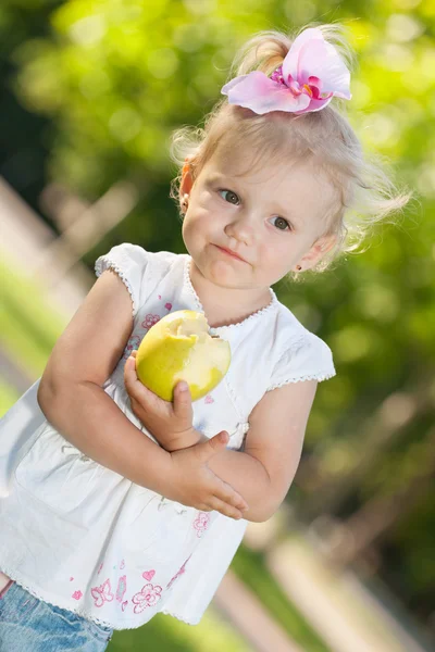 Little girl with an apple in the park — Stock Photo, Image