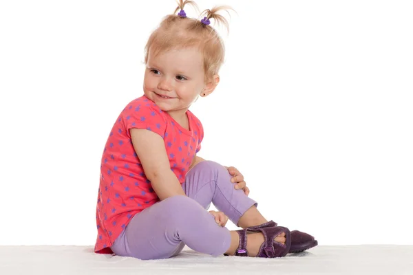 Cheerful little girl sitting on the white — Stock Photo, Image