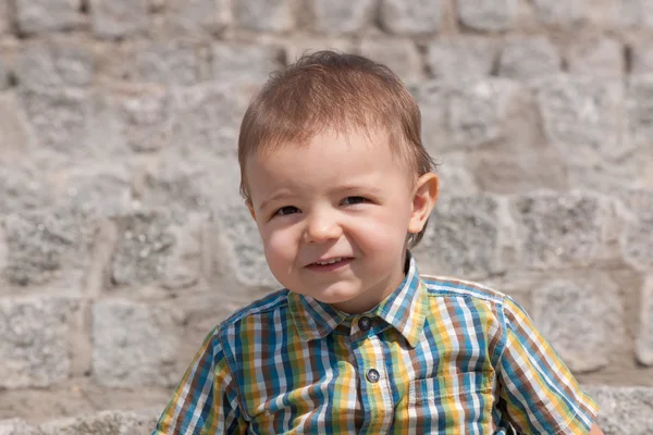 Ritratto di un bambino carino contro il muro di pietra — Foto Stock