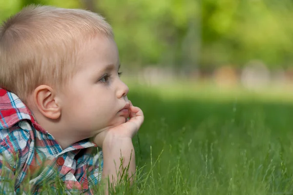 Tankeväckande liten pojke på gräset — Stockfoto