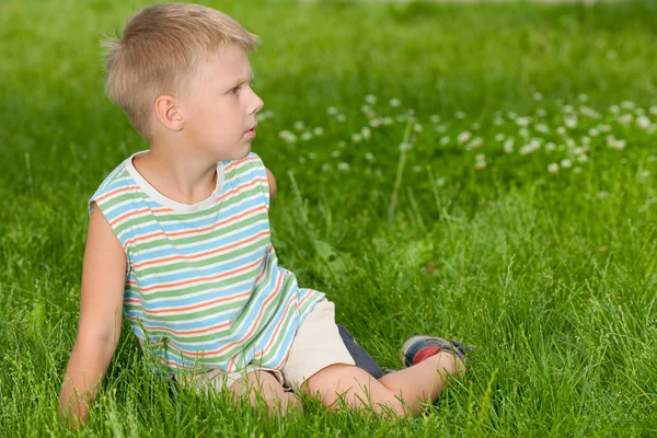 Pojke på gräset ser åt sidan — Stockfoto