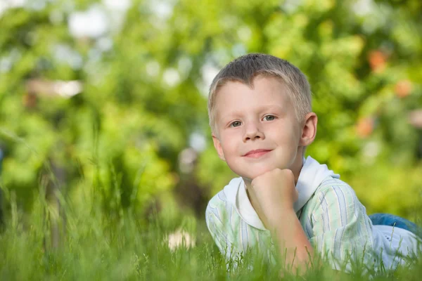 Pensive boy on the green grass — Stok fotoğraf