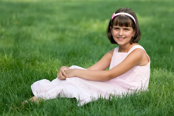 Girl in pink resting on the green grass — Stock Photo, Image