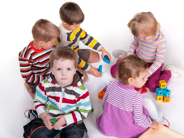 Cinco crianças brincando de brinquedos coloridos — Fotografia de Stock