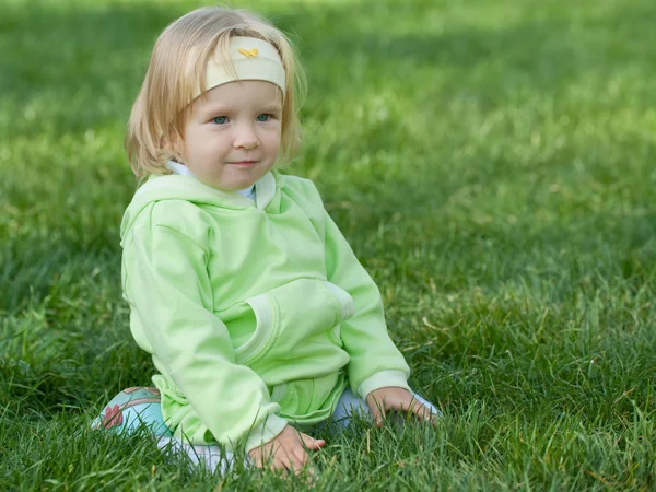 Retrato de una niña bonita en verde en la hierba verde — Foto de Stock