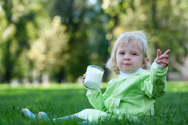 Portrait of a little girl drinking milk in the park — Stock Photo, Image