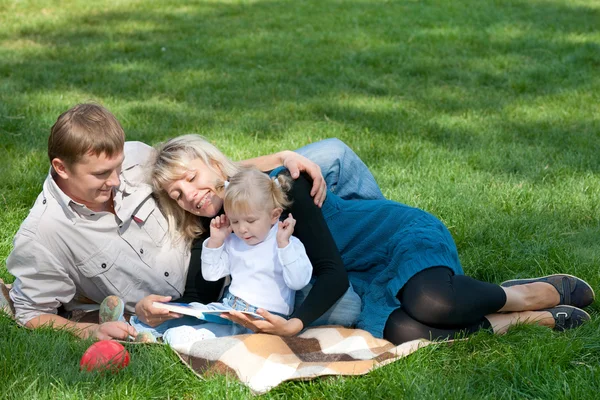 Mãe lendo para sua família lá fora — Fotografia de Stock