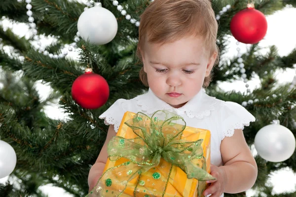Criança segurando um presente de Natal em uma árvore de ano novo — Fotografia de Stock