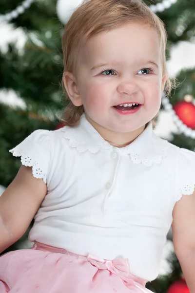 Fröhliches kleines Mädchen am geschmückten Weihnachtsbaum — Stockfoto